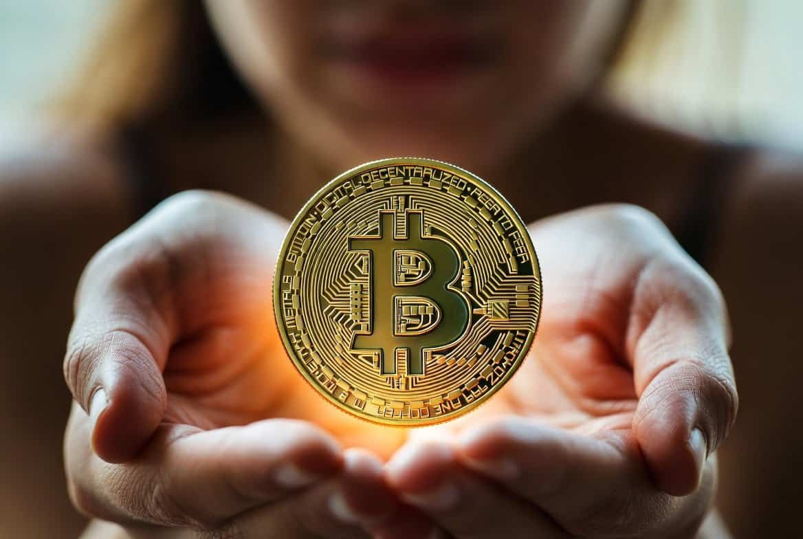 Young woman holding a golden Bitcoin coin in cupped hands - bitcoin price analysis April 2026