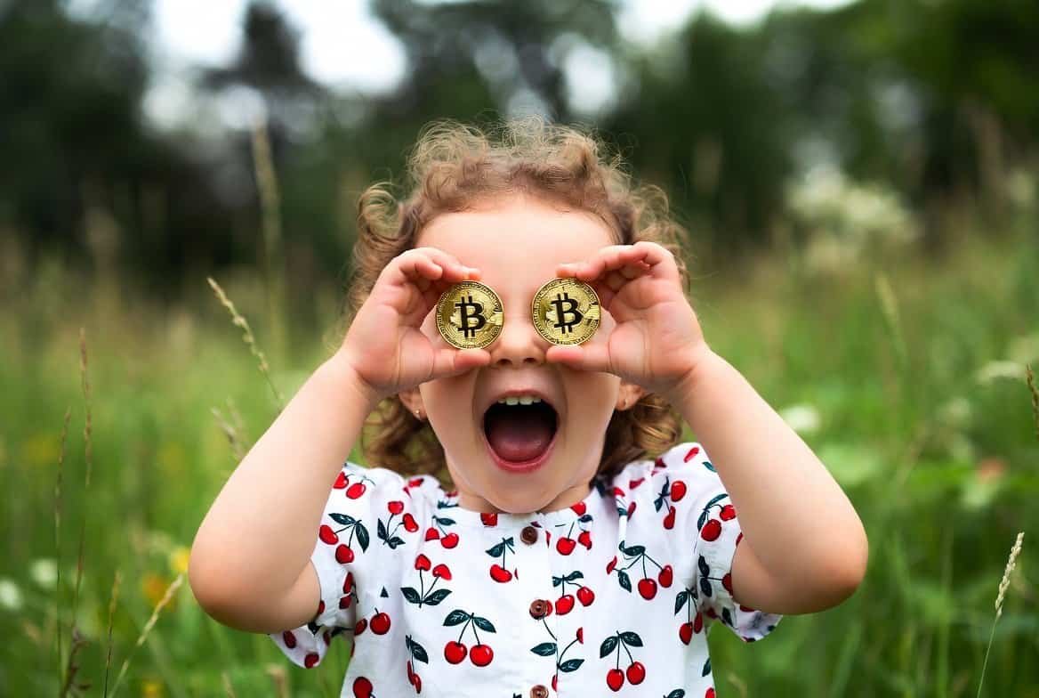 Girl holding two golden Bitcoin coins up to her eyes in a sunny meadow - Bitcoin price analysis April 2026
